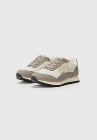 Sneakers beige e grigi con materiali in rete e scamosciato, caratterizzati da una suola testurizzata, design con lacci e un logo impresso sul lato.