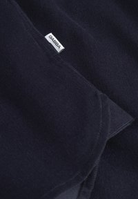Tejido azul marino con una textura suave y un diseño acanalado. Presenta una etiqueta blanca de GABBA cosida en el borde.