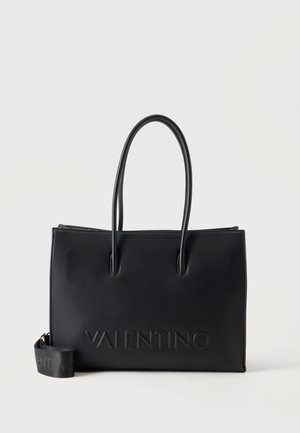 Sac cabas noir Valentino avec deux longues anses et le nom de la marque embossé sur le devant, présenté sur un fond clair uni.
