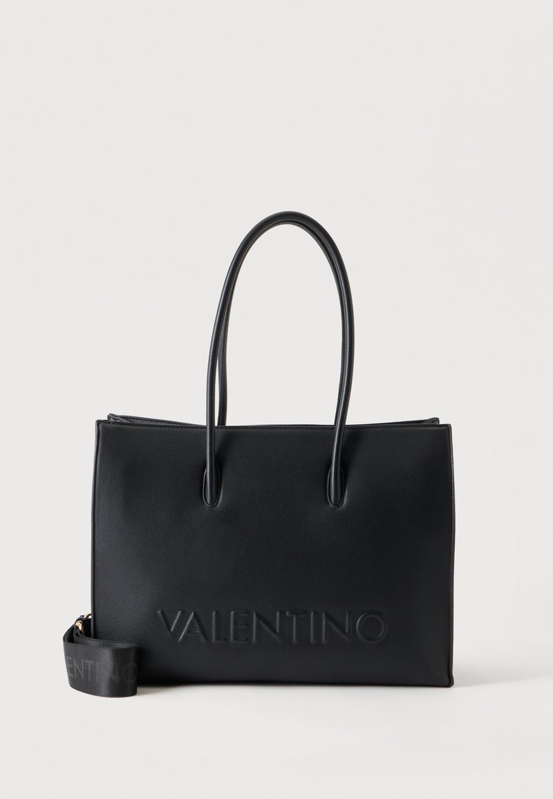 Μαύρη τσάντα Valentino tote με δύο μακριές λαβές και ανάγλυφο το όνομα της μάρκας στο μπροστινό μέρος, απεικονίζεται σε απλό ανοιχτό φόντο.