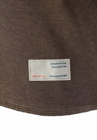 Tessuto di cotone marrone con una finitura testurizzata, dotato di un'etichetta bianca cucita con "odd molly", "celebrate voi stessi" e "unicorporato" in blu e rosso.