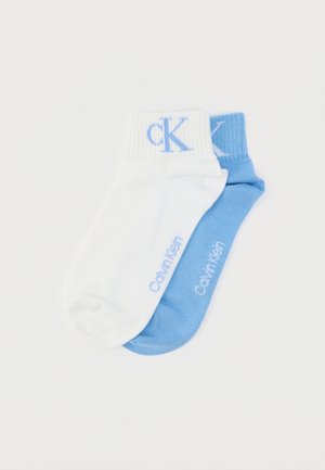 Κάλτσες αστραγάλου Calvin Klein με μία λευκή κάλτσα και μία ανοιχτό μπλε. Κάθε μία έχει ριμπ μανσέτες και κεντημένο λογότυπο σε αντίστοιχα χρώματα.