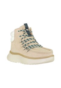 Botas de tobillo de ante beige con un cuello de pelaje sintético blanco texturizado, cordones a cuadros verdes y grises, y suela de goma blanca gruesa.