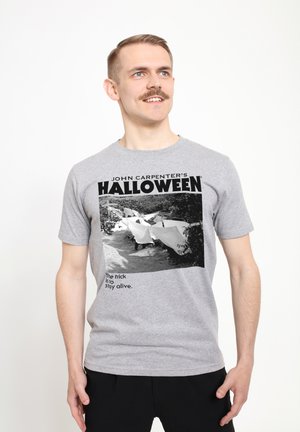 Grå bomulds t-shirt med et sort-hvidt grafik fra "Halloween" filmen, tekst underneden der siger "Tricket er at overleve."