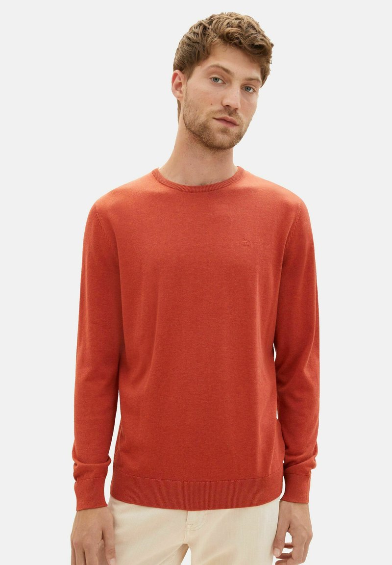 Rode gebreide trui met een ronde hals, lange mouwen, geribbelde manchetten en onderrand. Zachte textuur en minimale branding op de borst.