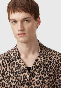 Korte ærmede skjorte i leopardmønster i beige og sort, med en afslappet krave, knaplukning og subtil tekstur.