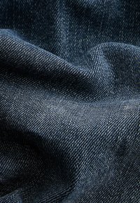Sötétkék farmer textil, sima, enyhén textúrált felülettel, klasszikus twill szövési mintával és finom árnyalatbeli eltérésekkel.