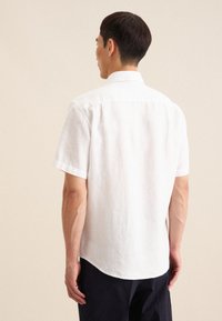 Witte linnen shirt met korte mouwen, voorzien van een button-down kraag, detail in de rug, en een afgeronde zoom. De stof heeft een gladde textuur.