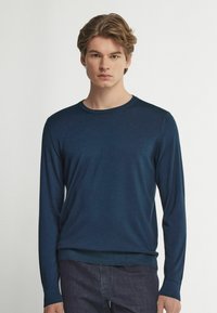 Mörkblå långärmad tröja med rund halsringning, tillverkad av mjukt stickat material. Har ribbade ärmslut och nederkant, med en slät yta och minimala detaljer.