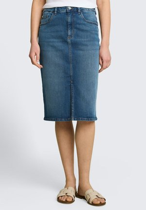 Blauwe spijkerrok tot op de knie, gecombineerd met beige instapsandalen, weergegeven van taille tot onderbenen tegen een effen achtergrond.