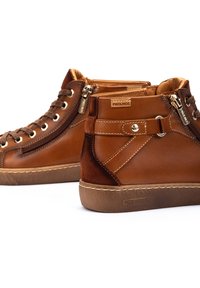 Bottines montantes en cuir marron avec fermetures éclair et design à lacets. Textures lisses et en nubuck, avec une étiquette logo et des semelles en caoutchouc beige.