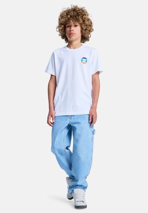 Biała bawełniana koszulka z krótkimi rękawami i okrągłym dekoltem, z kolorowym, okrągłym logo. Jasnoniebieskie luźne jeansy i szare tenisówki.