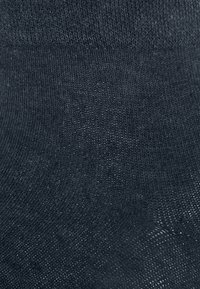 Dunkelgraue gestrickte Socken mit glatter Textur, ausgestattet mit einem gerippten Bund und feinen Nähten überall. Keine sichtbaren Muster oder Akzente.