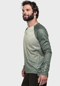 Langärmliges Sportshirt in Hell- und Dunkelgrün, mit strukturiertem Stoff und Logo am Ärmel. Für aktive Nutzung entworfen.