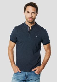 Polo azul marino con un patrón texturizado, mangas cortas y cuello con botones. Detallado con ribete en contraste y un logo en el pecho.