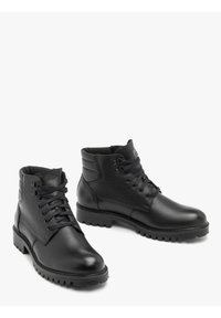 Botas de cuero negro con un acabado texturizado, punta redonda y diseño de cordones. Cuentan con un cuello acolchado en el tobillo y suela de goma resistente y con patrón.