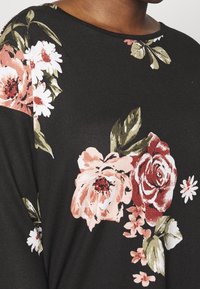 Black fabric with large, colorful floral patterns featuring pink roses and white daisies; round neckline and soft texture.