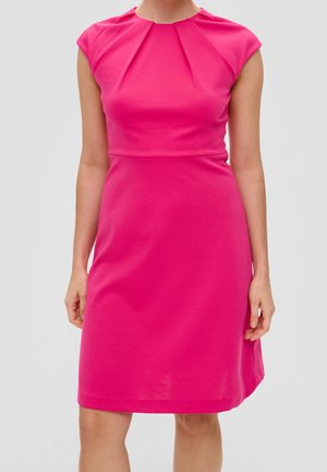 Frau trägt ein ärmelloses, knielanges, leuchtend pinkes Kleid mit plissierten Details am Ausschnitt vor einem schlichten Hintergrund.