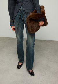 Dunkelblau kariertes Hemd, hoch taillierte, verwaschene blaue Jeans, schwarze spitze Schuhe und eine braune Kunstpelztasche.