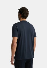 T-shirt in cotone blu navy con maniche corte, scollatura tonda e tessuto testurizzato. Vista da dietro, con dettagli minimi.