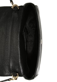 Svart läderhandväska med texturerad yta, prydd med guldfärgad hårdvara och ett tygfoder med ett präglat mönster. Öppen toppdesign.