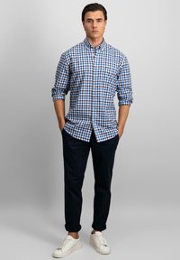Blauw en wit geruit overhemd met knopen, lange mouwen, katoen stof, opgerolde manchetten, gedragen met marineblauwe broek en witte sneakers.