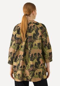 Bloemmotief shirt in donkere stof, met grote dierenmotieven in roze en groen. Driekwart mouwen met een relaxte pasvorm en een detail aan de achterkant.