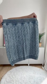 Pulover iz volne z kabelskim pletenjem v svetlo modri barvi z rebrastim temno modrim ovratnikom. Ima teksturirane vzorce po vsej površini in ravno prileganje.