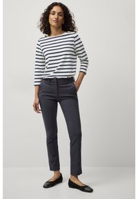 Marineblauwe op maat gemaakte broeken gecombineerd met een wit met marineblauwe gestreepte long-sleeve shirt. De outfit wordt compleet gemaakt met zwarte platte schoenen.