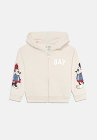 Krémová detská mikina na zips s kapucňou, predn�ými vreckami, logom GAP na hrudi a grafikou Mickey a Minnie Mouse na rukávoch.