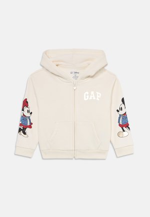 Felpa con zip per bambini di colore crema, con cappuccio, tasche frontali, logo GAP sul petto e grafiche di Topolino e Minni sulle maniche.