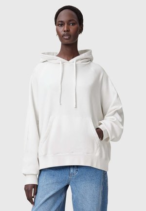 Witte hoodie met een voorzak, relaxte pasvorm en een trekkoord; gecombineerd met lichtblauwe spijkerbroek. Soepele stoftextuur.