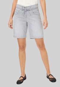 Lichtgrijze denim shorts met een verstelbare tailleband, twee zijzakken en omgeslagen zoom. Draagt met zwarte mesh ballerina's.