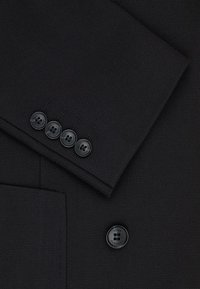 Czarna marynarka z tkaniny o strukturalnym wykończeniu. Posiada cztery czarne guziki na mankiecie oraz jeden większy guzik na frontowej kieszeni do zapięcia.