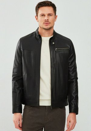 Black leather jacket with a high collar, front zipper, and two side pockets. Features a zippered chest pocket and smooth texture.