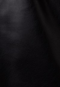 Gros plan de la texture en cuir noir montrant un grain fin et des plis naturels avec un reflet de lumière doux.