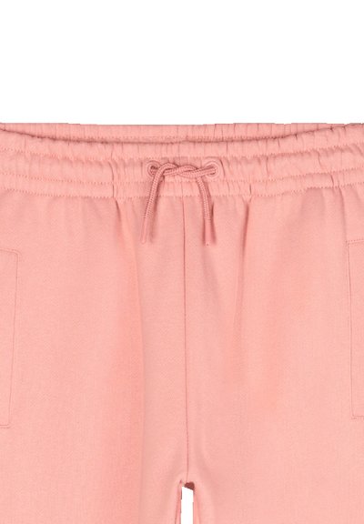 Pantalons de survêtement rose clair avec une taille élastique et un cordon de serrage, dotés de poches latérales et d'un tissu doux et texturé.