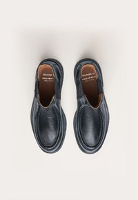 Zapatos negros de piel tipo slip-on con un acabado suave, puntera redonda, paneles laterales elásticos y detalles cosidos en el borde y la suela.