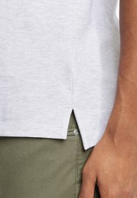Lys grå crew-neck t-shirt med en tekstureret finish, der har en sidesplit i kanten. Matchende med olivengrønne bukser.