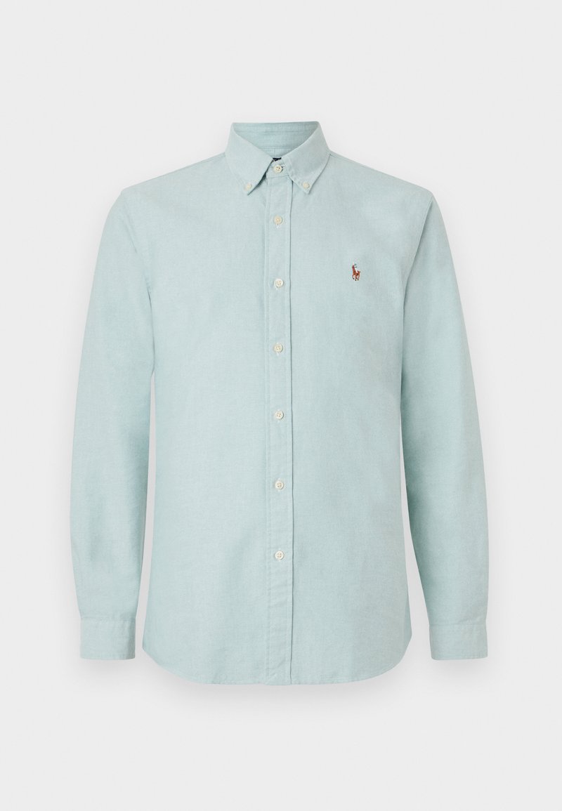 Lyseblå skjorte med knapper, krave, lange ærmer og et lille broderet logo på brystet. Lavet af blødt, tekstureret stof.