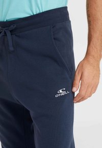 Tmavo modré joggingové nohavice so sťahovacím pásom, bočnými vreckami a bielym logom O'Neill. Vyrobené z mäkkej bavlnenej zmesi.