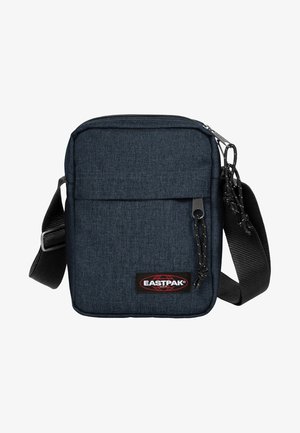 Mørkeblå stof crossbody taske med justerbar rem, lynlåslomme foran og Eastpak logo patch. Den har en rektangulær form og en tekstureret overflade.