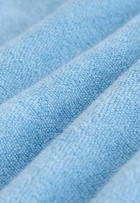 Svetlo modra teksturirana tkanina z rahlo dvignjenim tkanjem, ki prikazuje več gub in mehak, puhast videz.