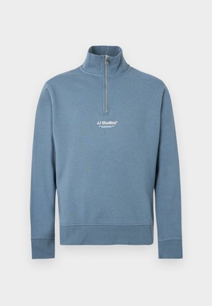 Light blue pullover sweatshirt with a half zipper and high collar. Features a white logo on the chest and ribbed cuffs and hem.