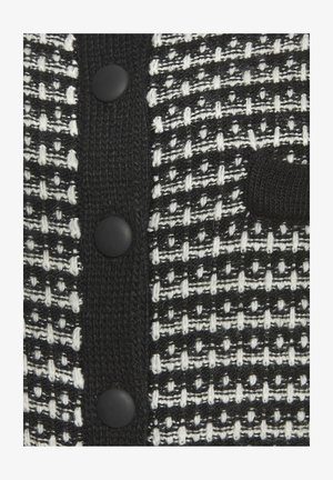 Cardigan testurizzato in bianco e nero con motivo a tessitura, cinque bottoni neri e un patch lavorato a maglia nero sulla parte anteriore.