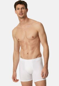 Boxer briefs blancs en tissu doux, avec une ceinture lisse et une coupe ajustée, dotés d'un design à poche avant.