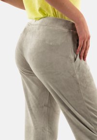 Pantalones de tela suave, de color gris claro, con una textura lisa, que cuentan con bolsillos laterales y una cintura cómoda, mostrados desde la parte de atrás.