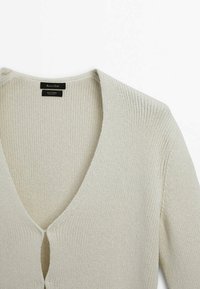 Hellbeige gestrickte Strickjacke mit V-Ausschnitt, geripptem Textur und Knopfverschluss vorne. Hergestellt aus einem Baumwollmischgewebe.