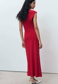 Rotes ärmelloses Maxikleid mit enganliegendem Oberteil und ausgestellt Rock, aus glattem Stoff gefertigt, mit einem tiefen Rückendesign und schmalen Trägern.