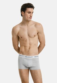 Gray boxer briefs with a snug fit, featuring a white waistband displaying the brand name "GANT" in navy blue. Plain design, cotton blend material.
